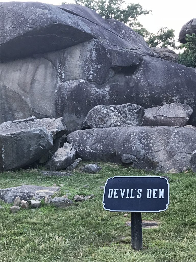 photo shows the immense boulders at devil's den, small wooden sign says devils den.